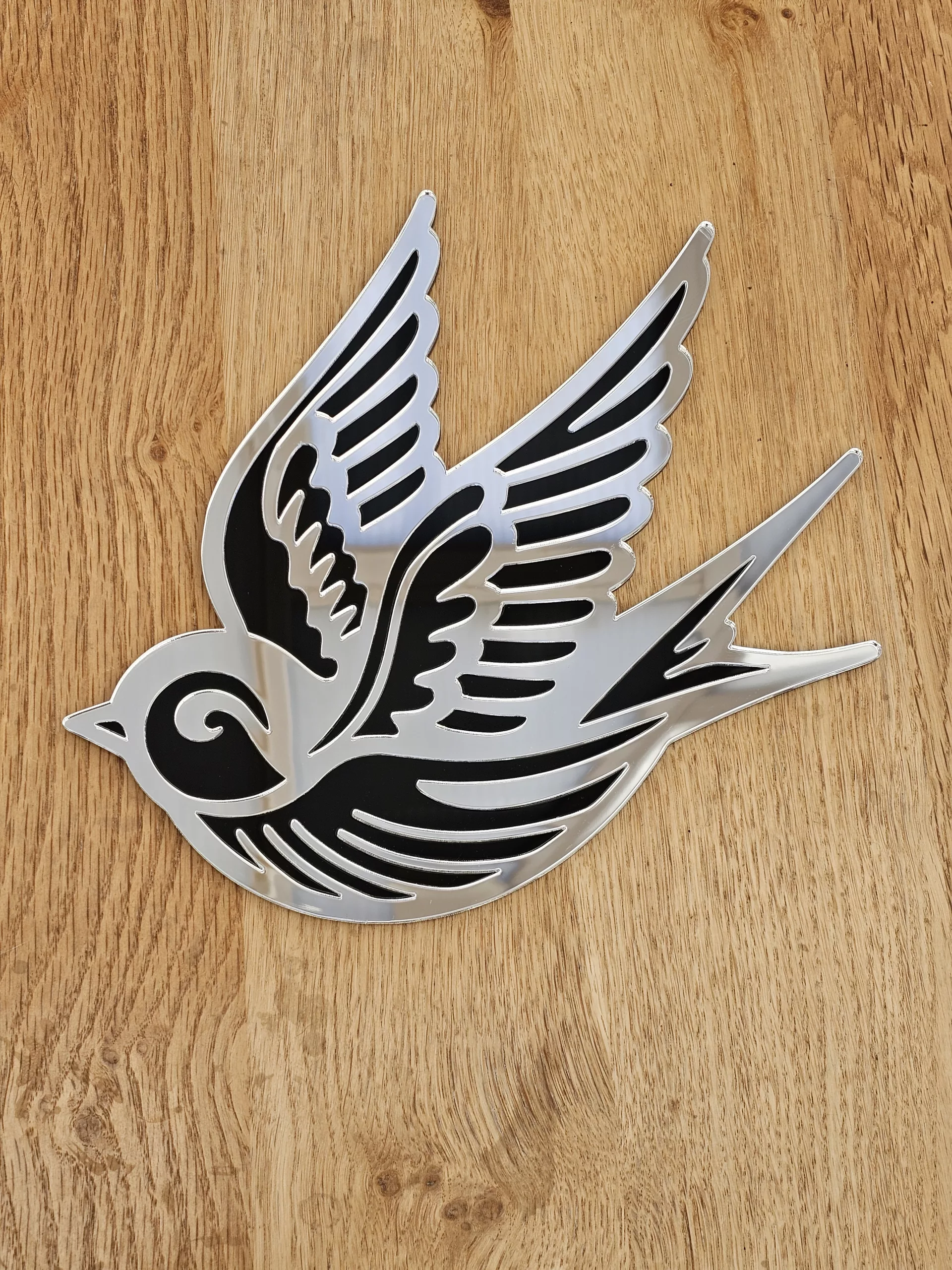 A mirror in the shape of a swallow, made in an old school tattoo style.