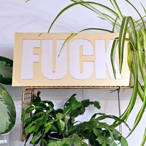 A mirror with the word FUCK in silver lettering with a gold mirror outline.