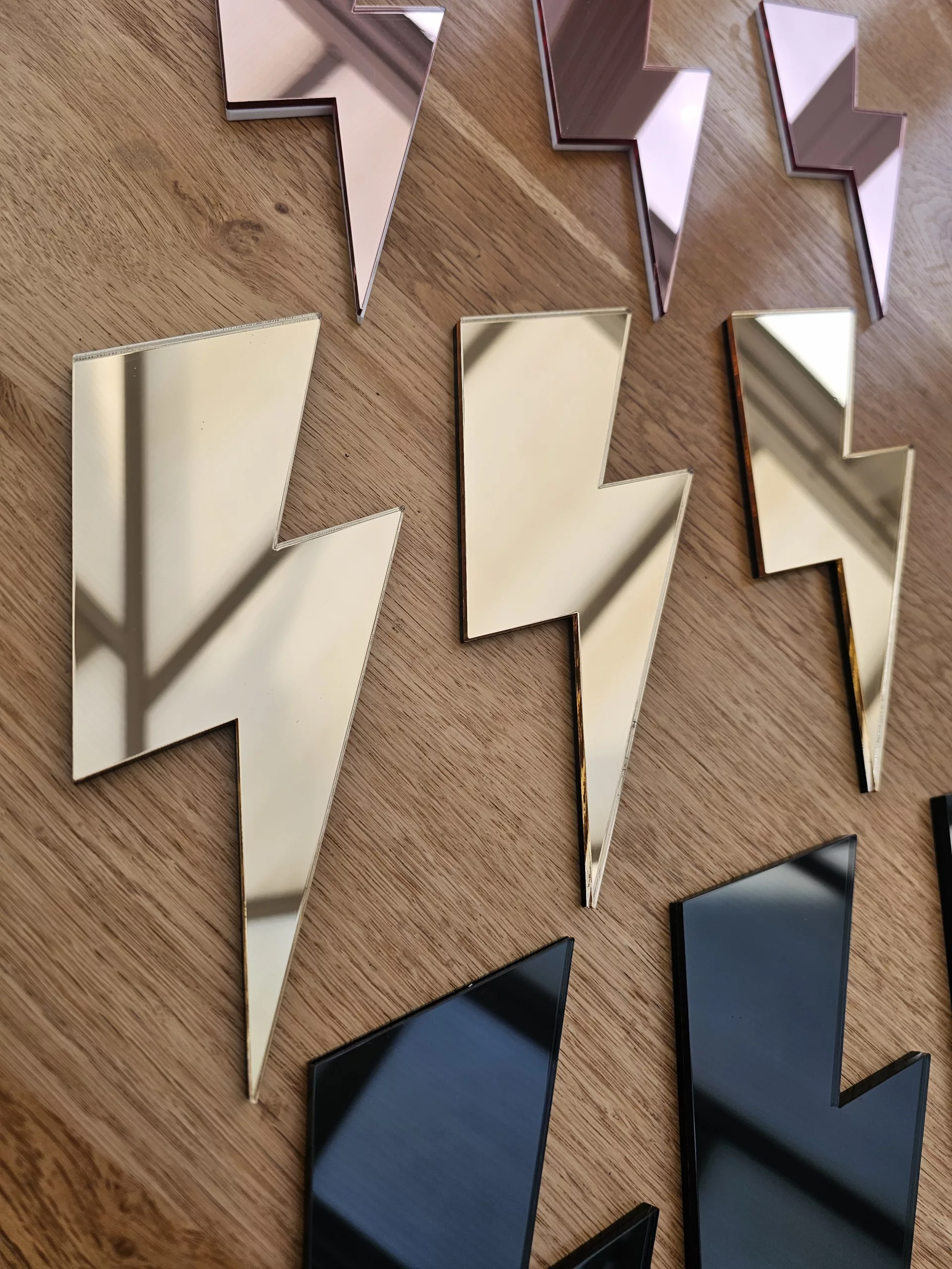 A set of 3 mirrors in the shape of a lightning bolt, in a variety of colours.