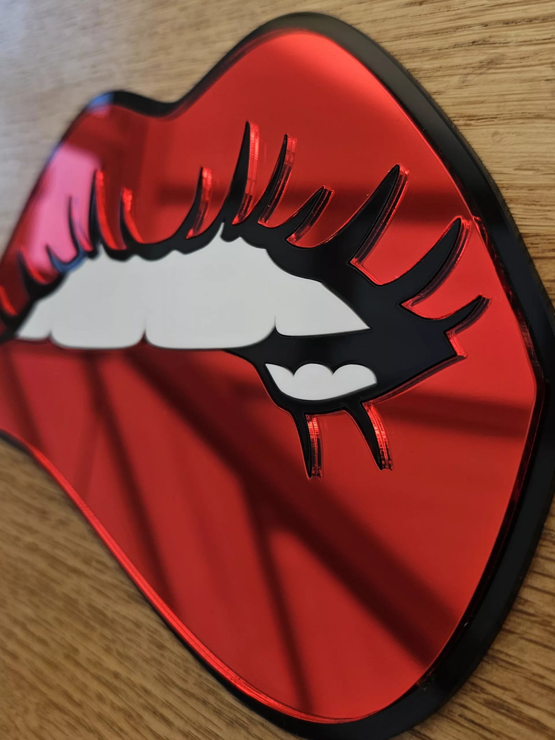 A handmade mirror in the shape of lips with the bottom lip being bitten. Made with mirror lips and glossy white teeth.