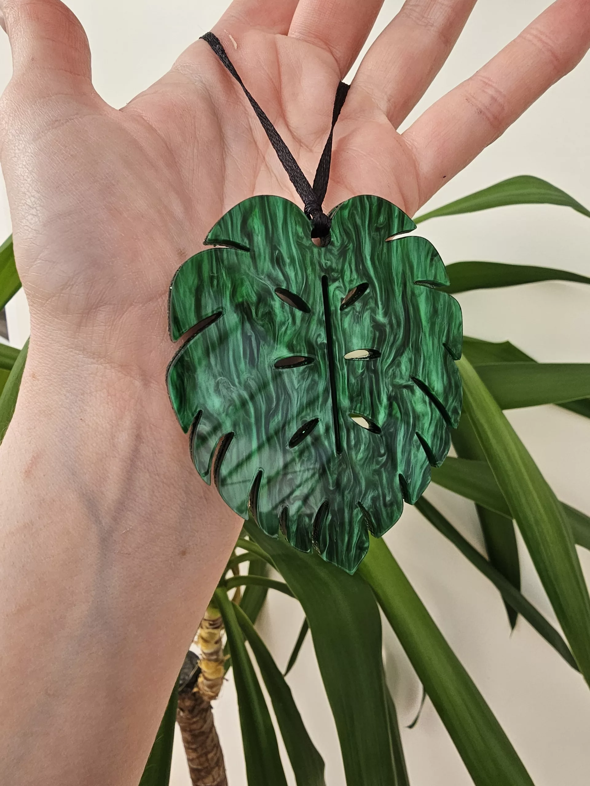 A plant charm or Christmas tree decoration in the shape of a Monstera Leaf.