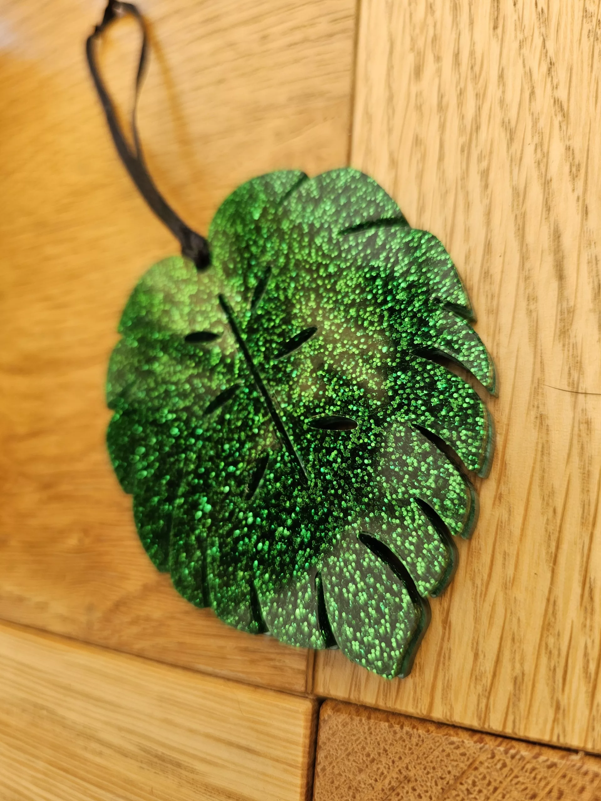 A plant charm or Christmas tree decoration in the shape of a Monstera Leaf.