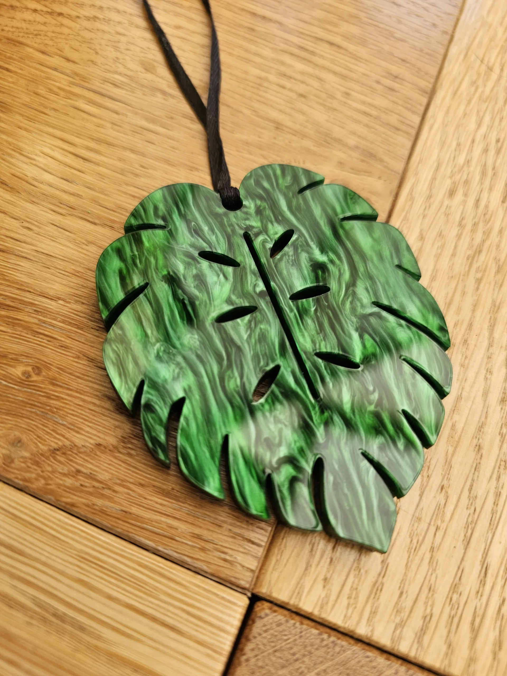 A plant charm or Christmas tree decoration in the shape of a Monstera Leaf.