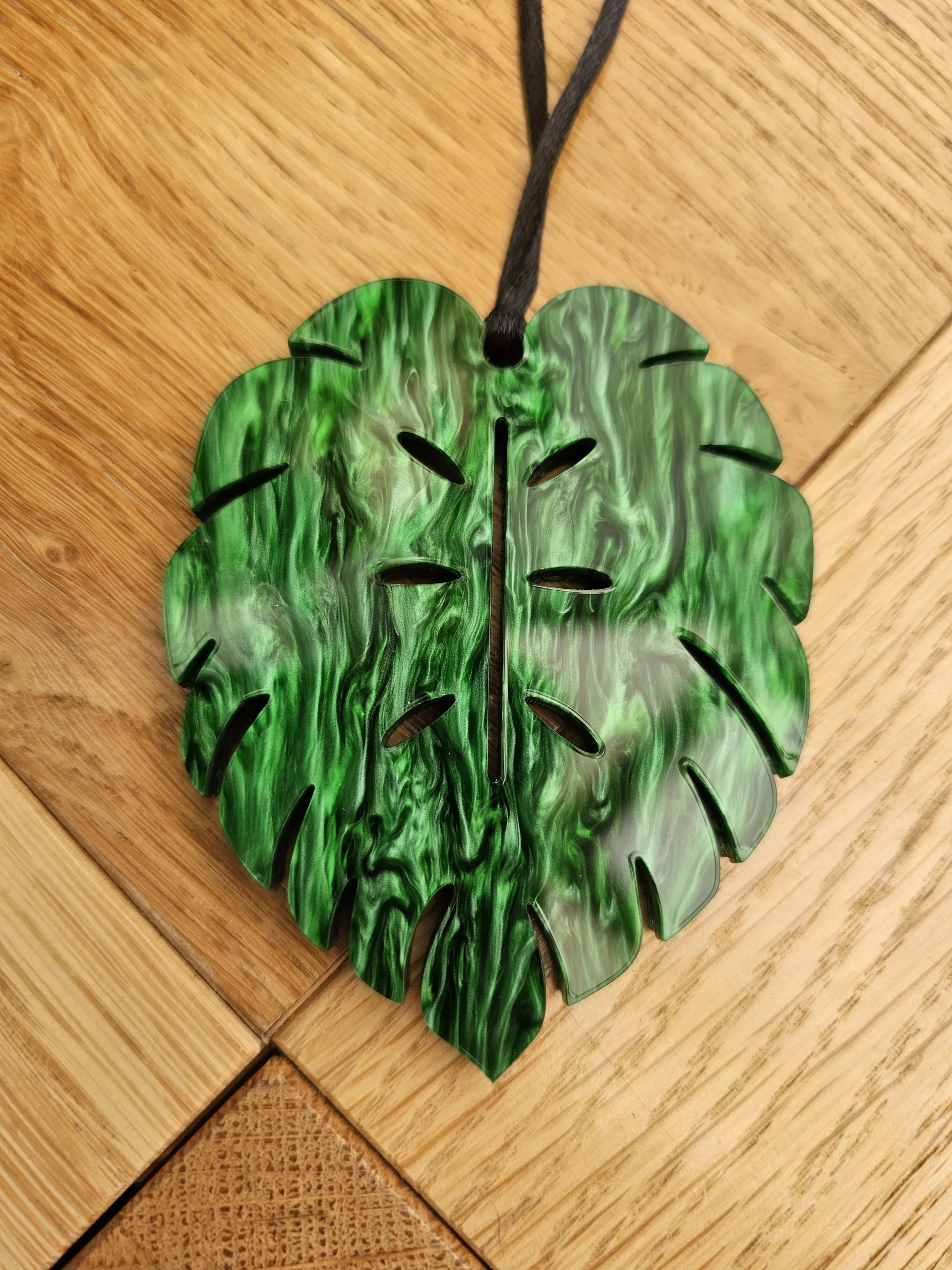 A plant charm or Christmas tree decoration in the shape of a Monstera Leaf.