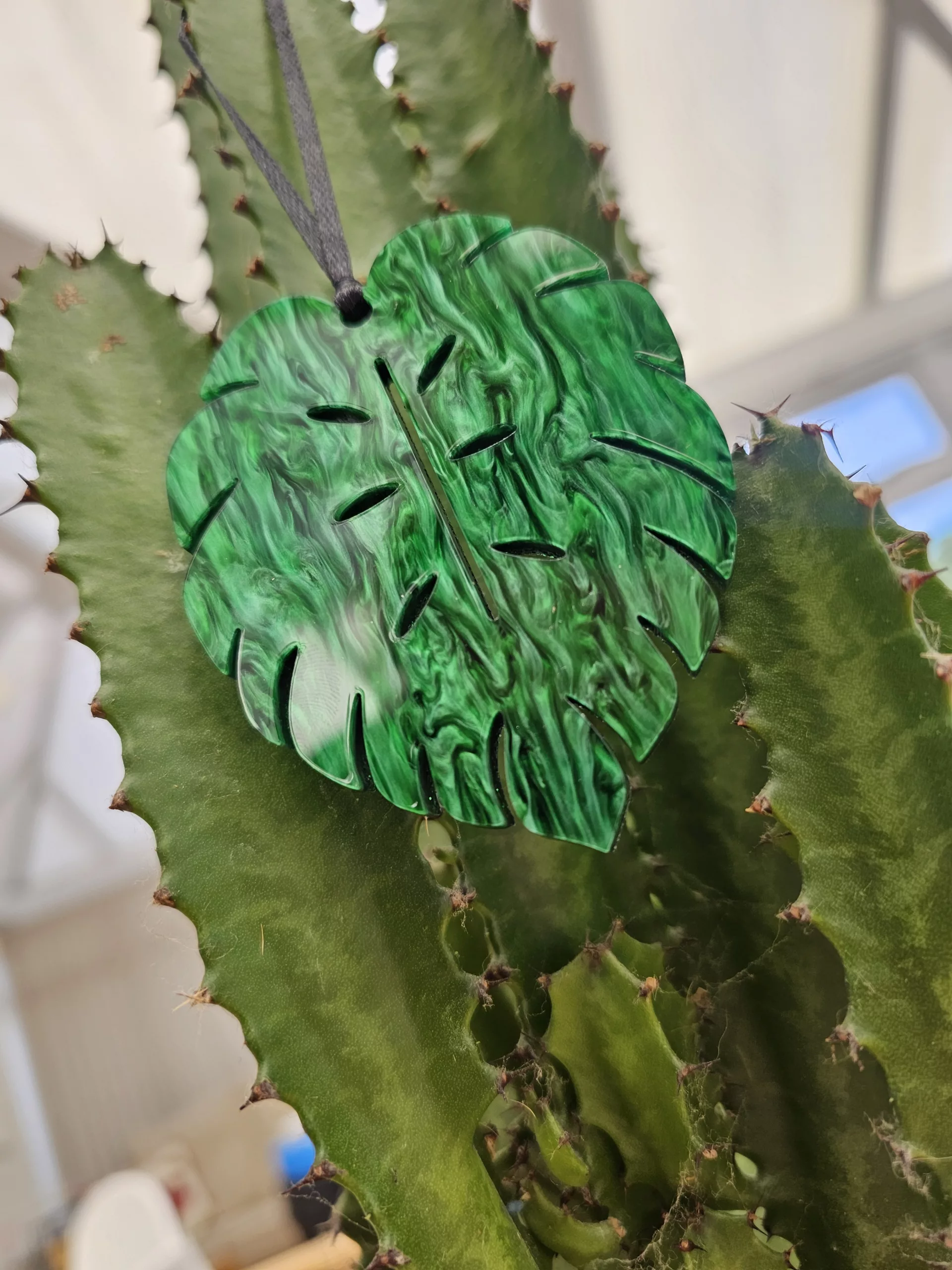 A plant charm or Christmas tree decoration in the shape of a Monstera Leaf.