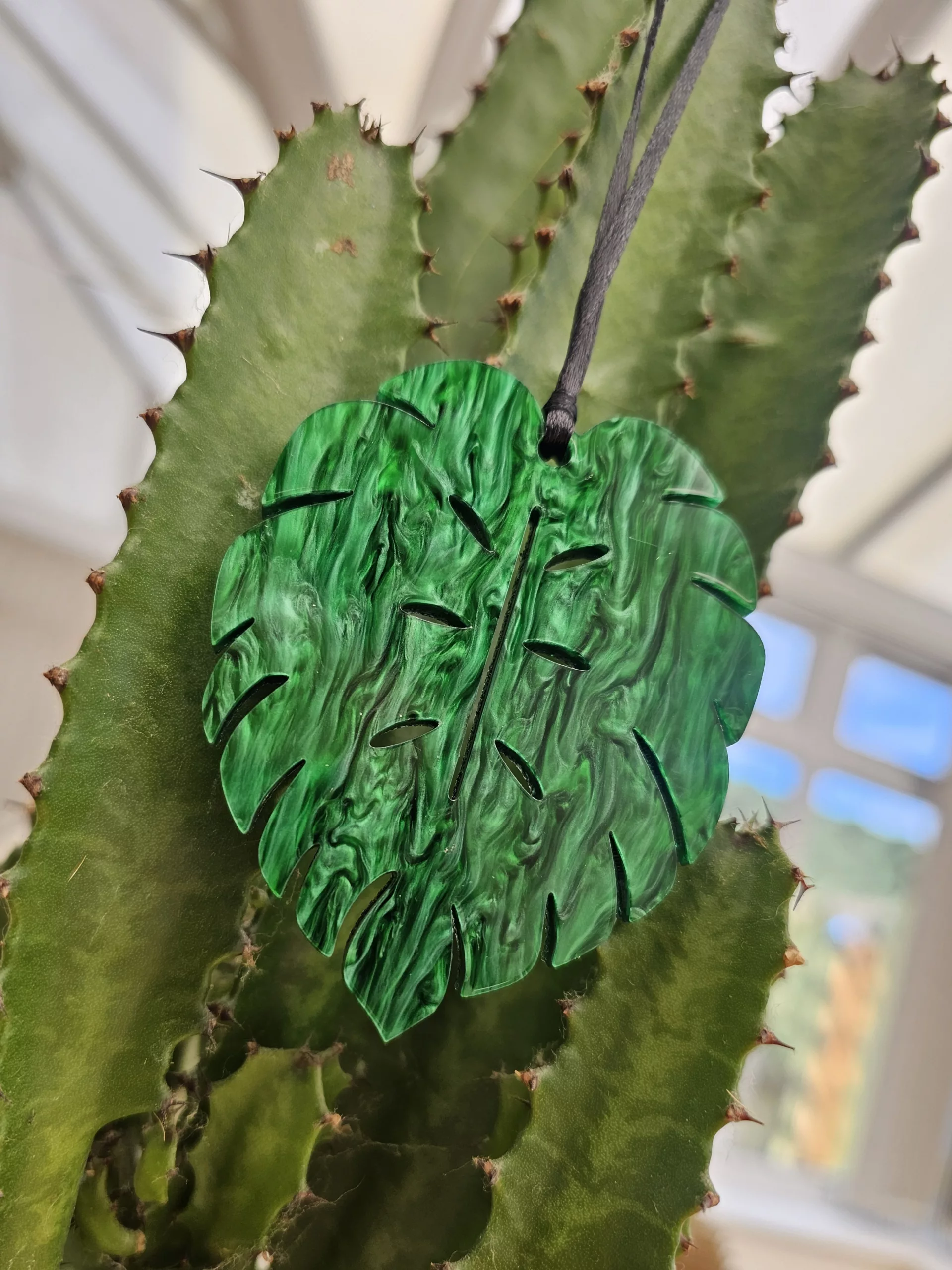 A plant charm or Christmas tree decoration in the shape of a Monstera Leaf.