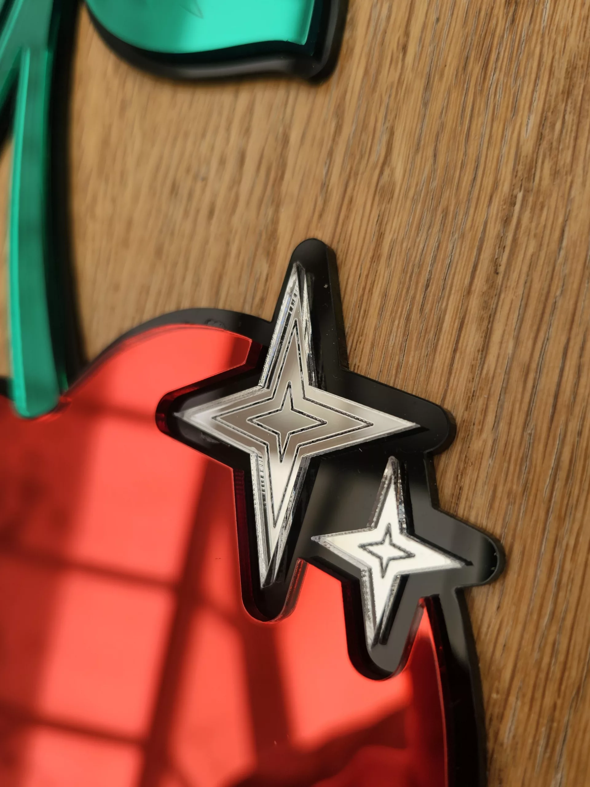 A piece of mirrored wall art in the shape of a cherry. With green leaves and silver sparkle details.