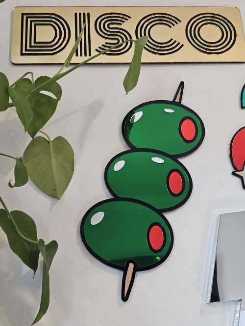 Mirrored wall art in the shape of olives on a cocktail stick.