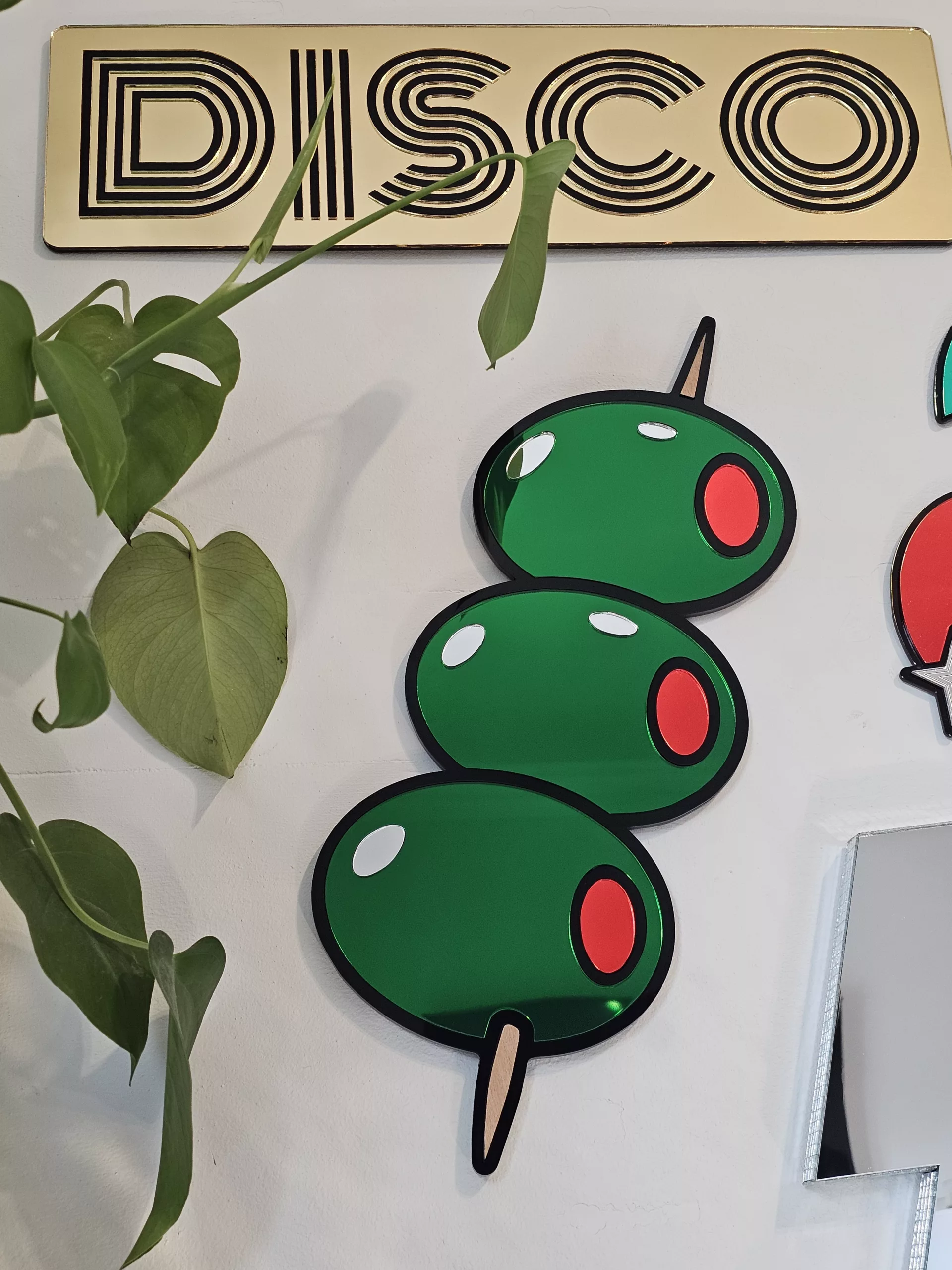 Mirrored wall art in the shape of olives on a cocktail stick.