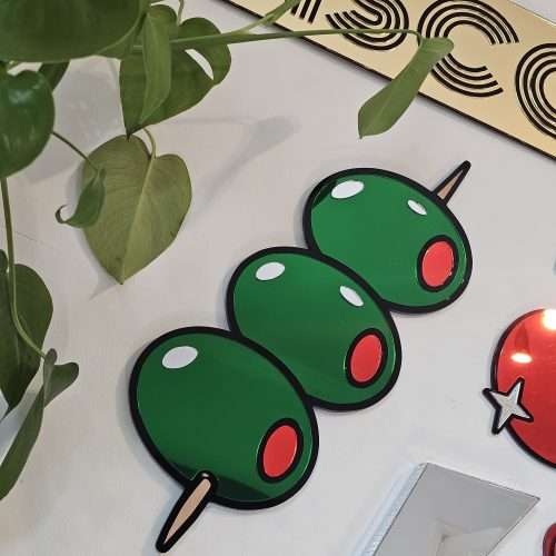 Mirrored wall art in the shape of olives on a cocktail stick.