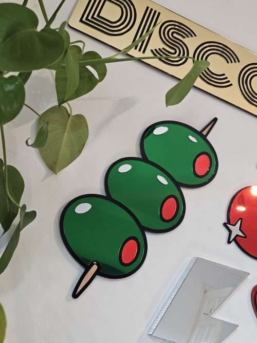 Mirrored wall art in the shape of olives on a cocktail stick.