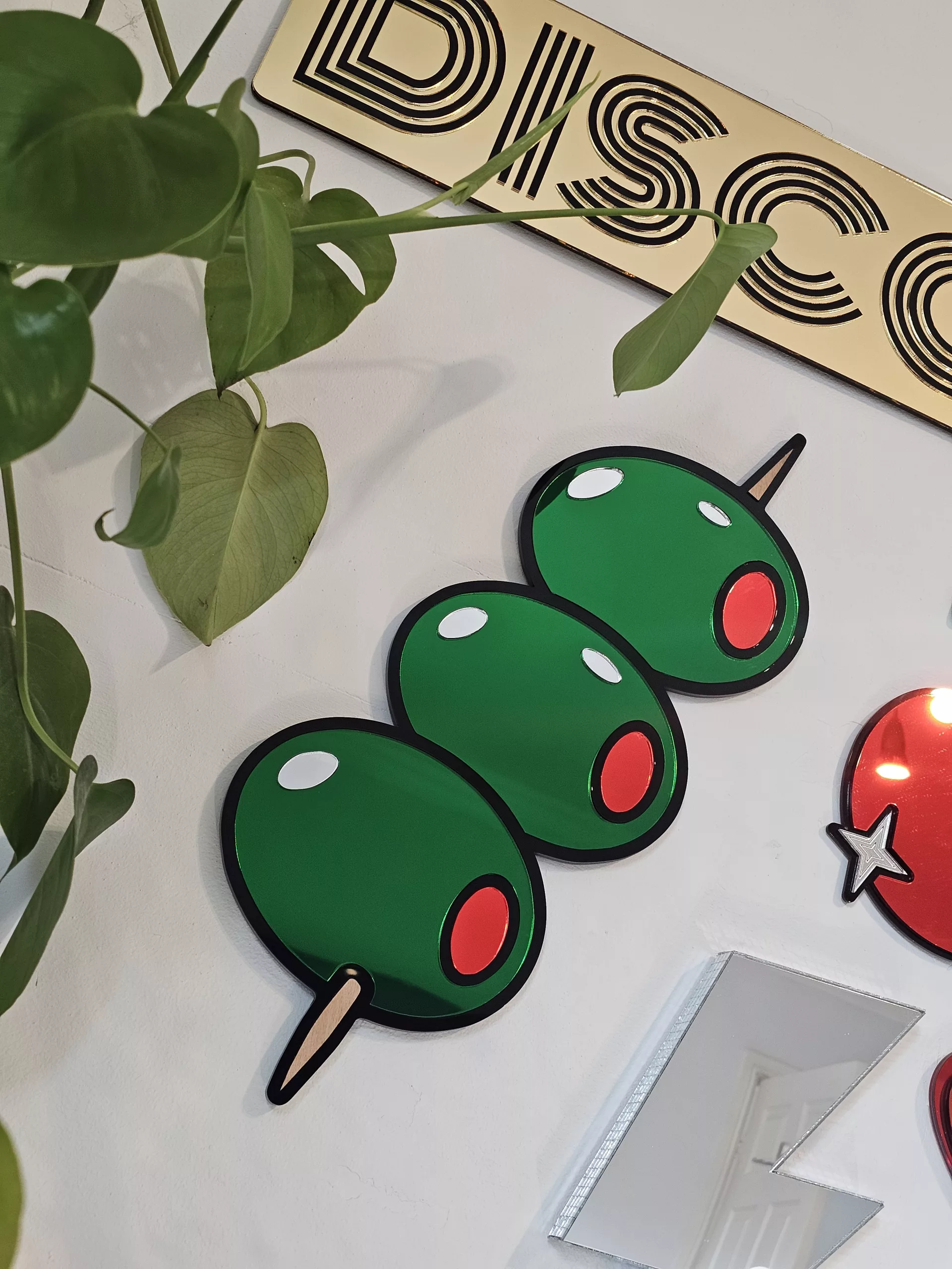 Mirrored wall art in the shape of olives on a cocktail stick.