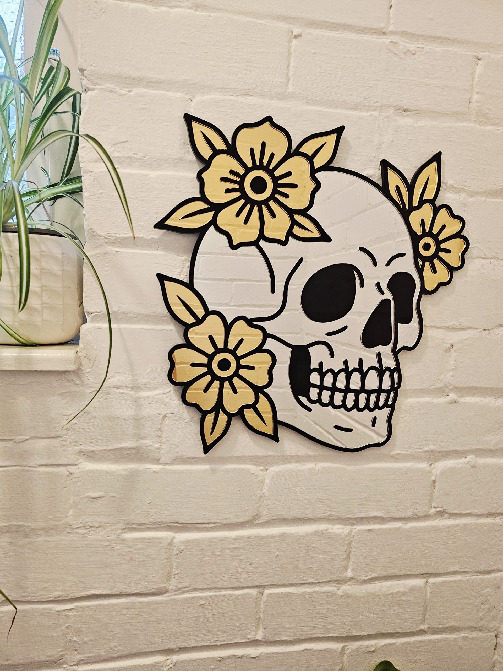 A mirror in the shape of a skull and flowers in an old school tattoo style.