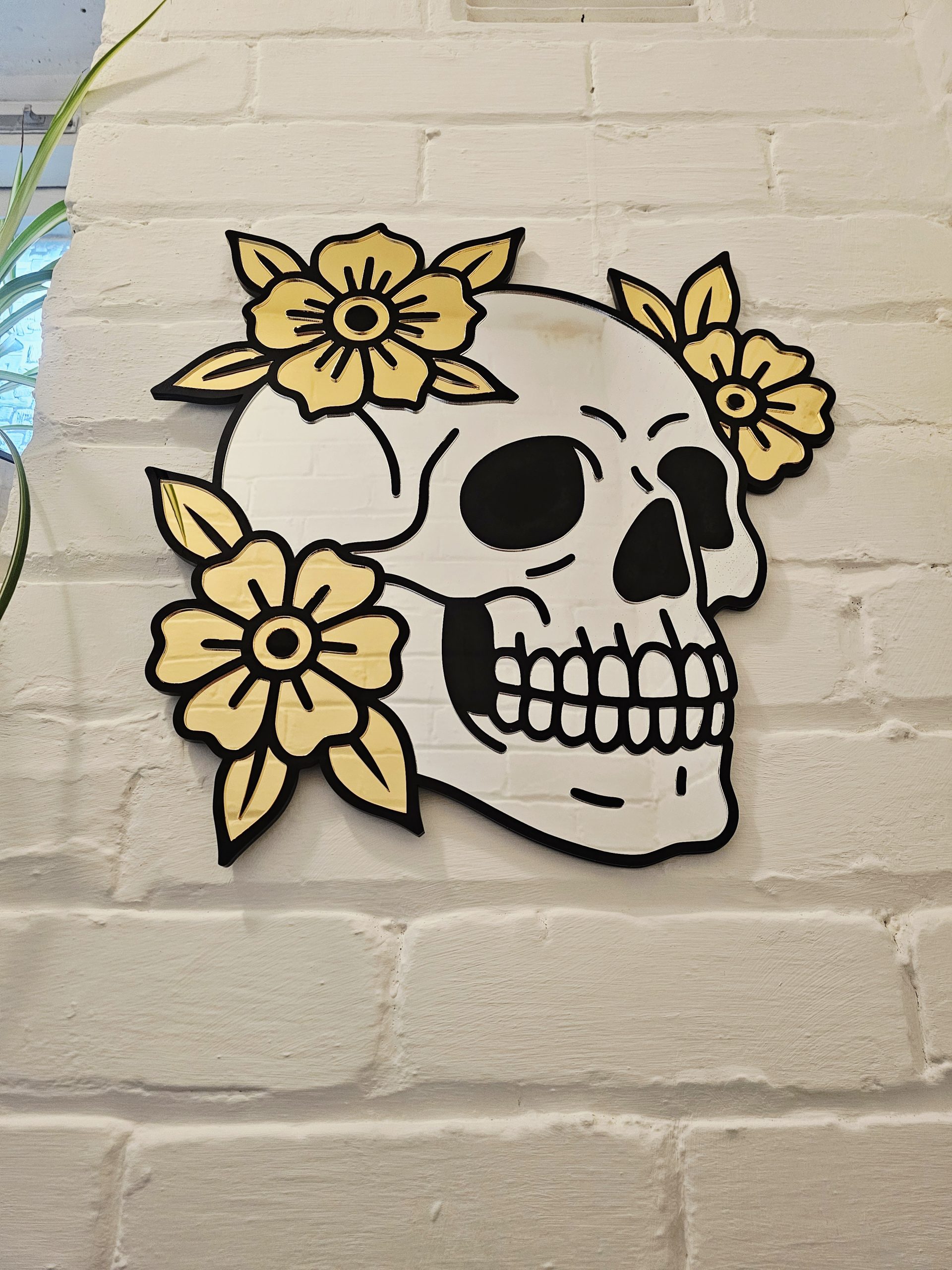 A mirror in the shape of a skull and flowers in an old school tattoo style.