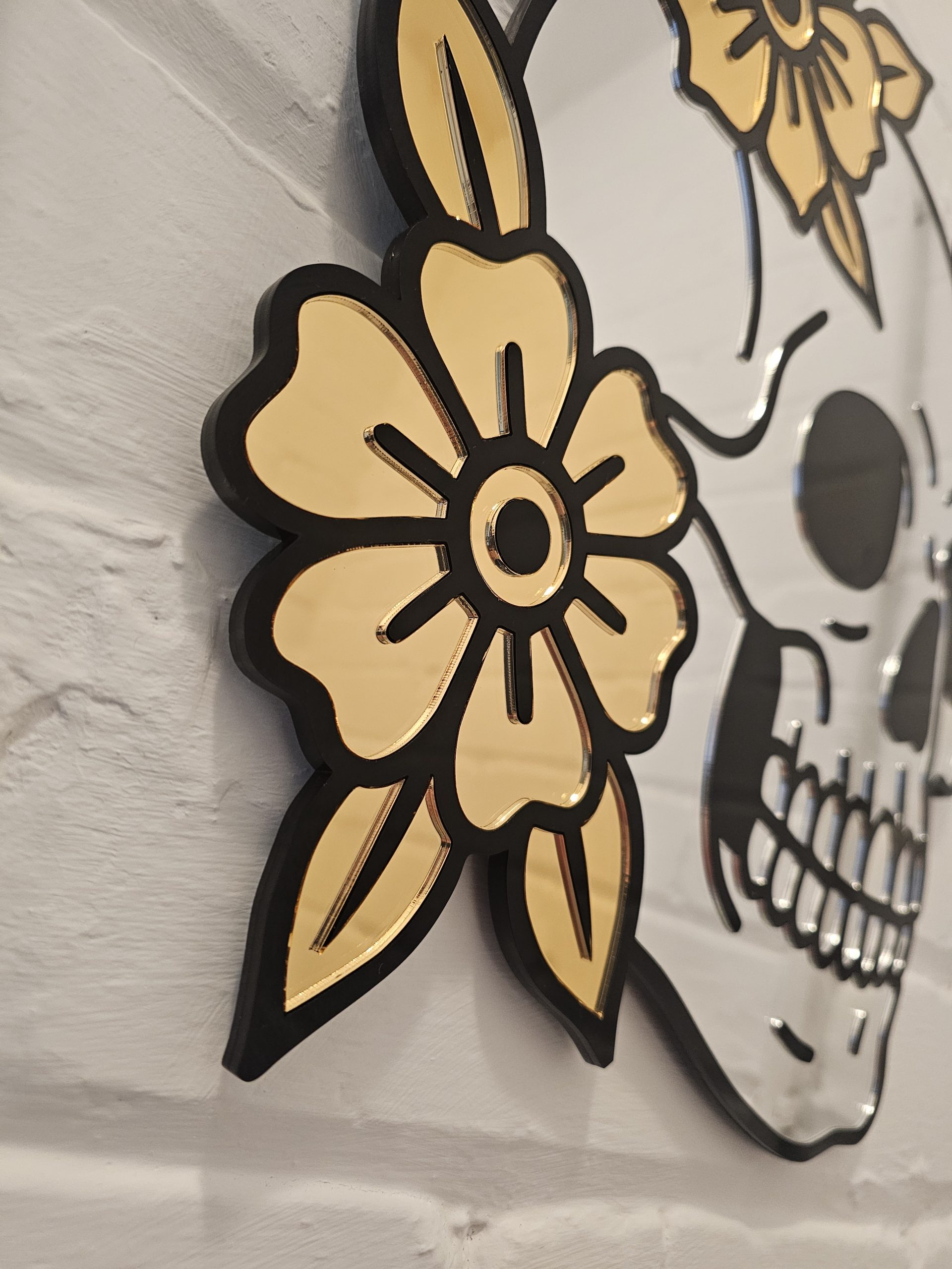 A mirror in the shape of a skull and flowers in an old school tattoo style.