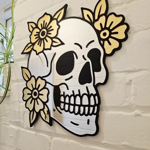 A mirror in the shape of a skull and flowers in an old school tattoo style.