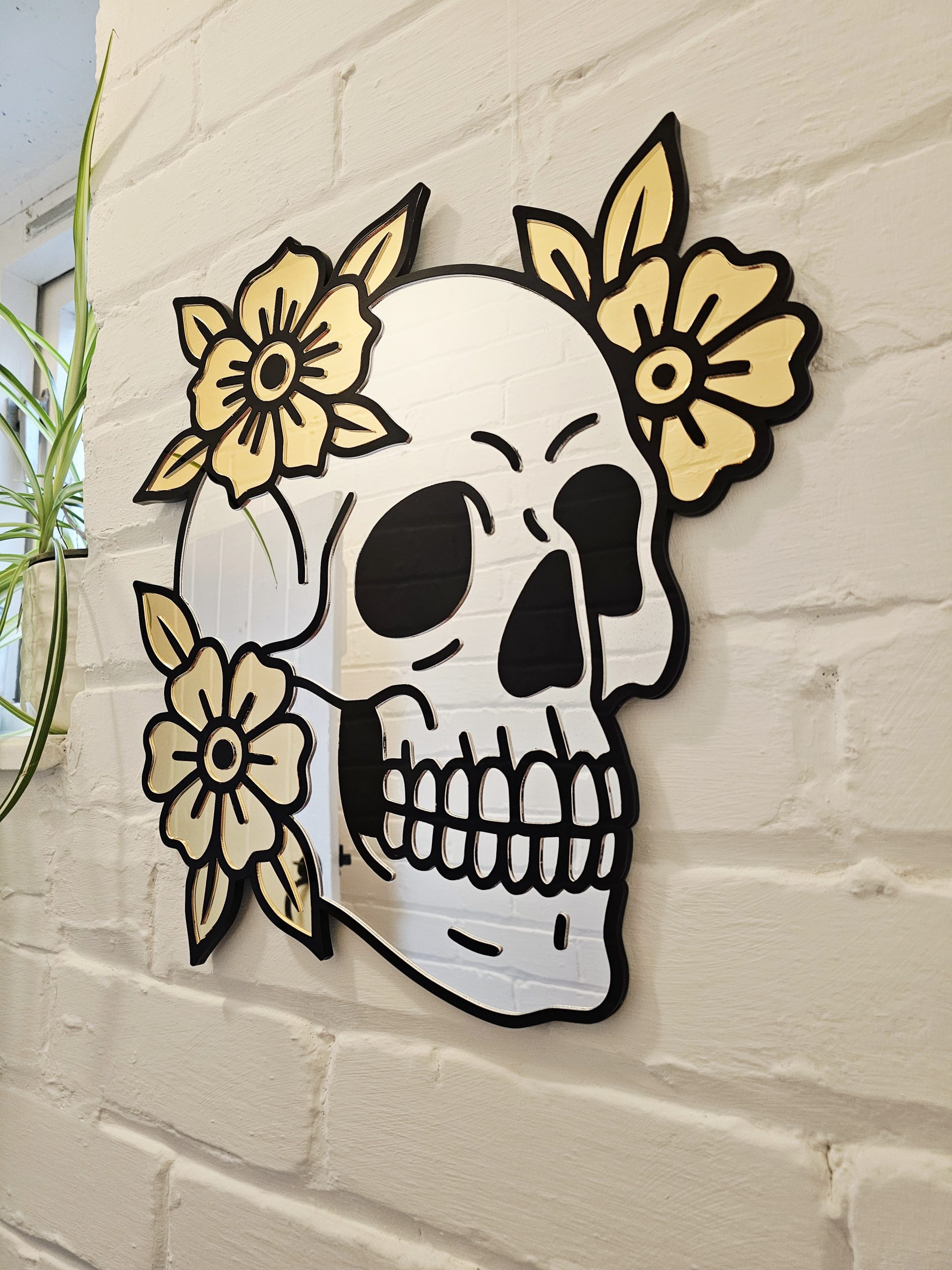 A mirror in the shape of a skull and flowers in an old school tattoo style.