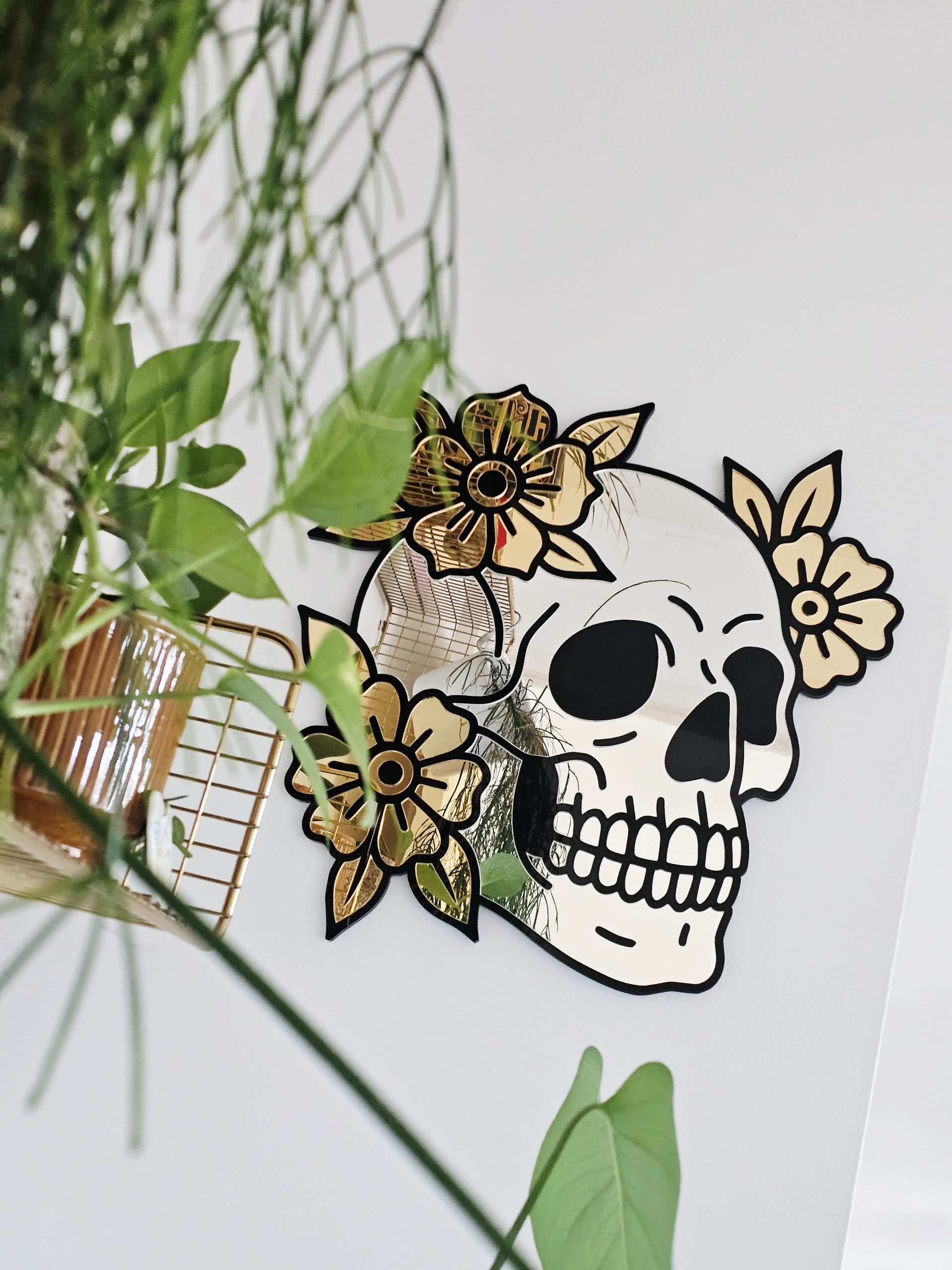 A mirror in the shape of a skull and flowers in an old school tattoo style.