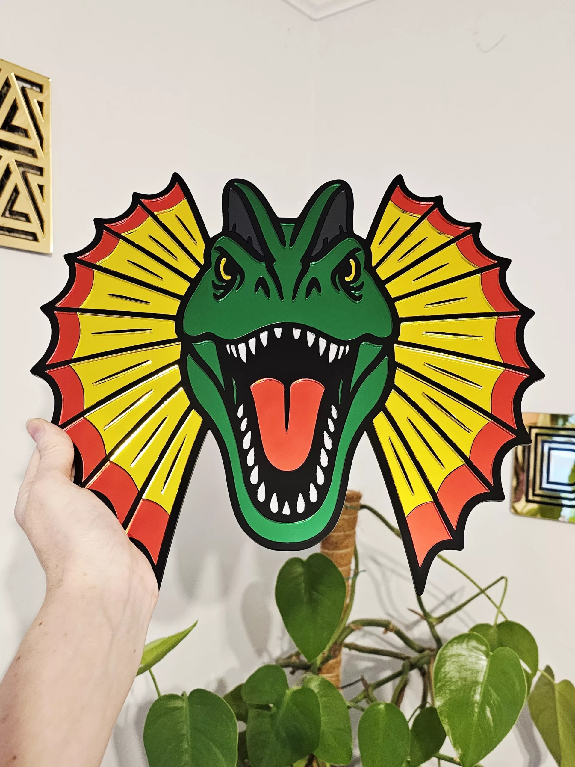 Colourful mirrored acrylic wall art in the shape of a Dilophosaurus dinosaur.
