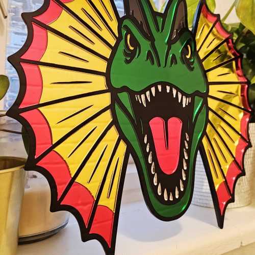 Colourful mirrored acrylic wall art in the shape of a Dilophosaurus dinosaur.