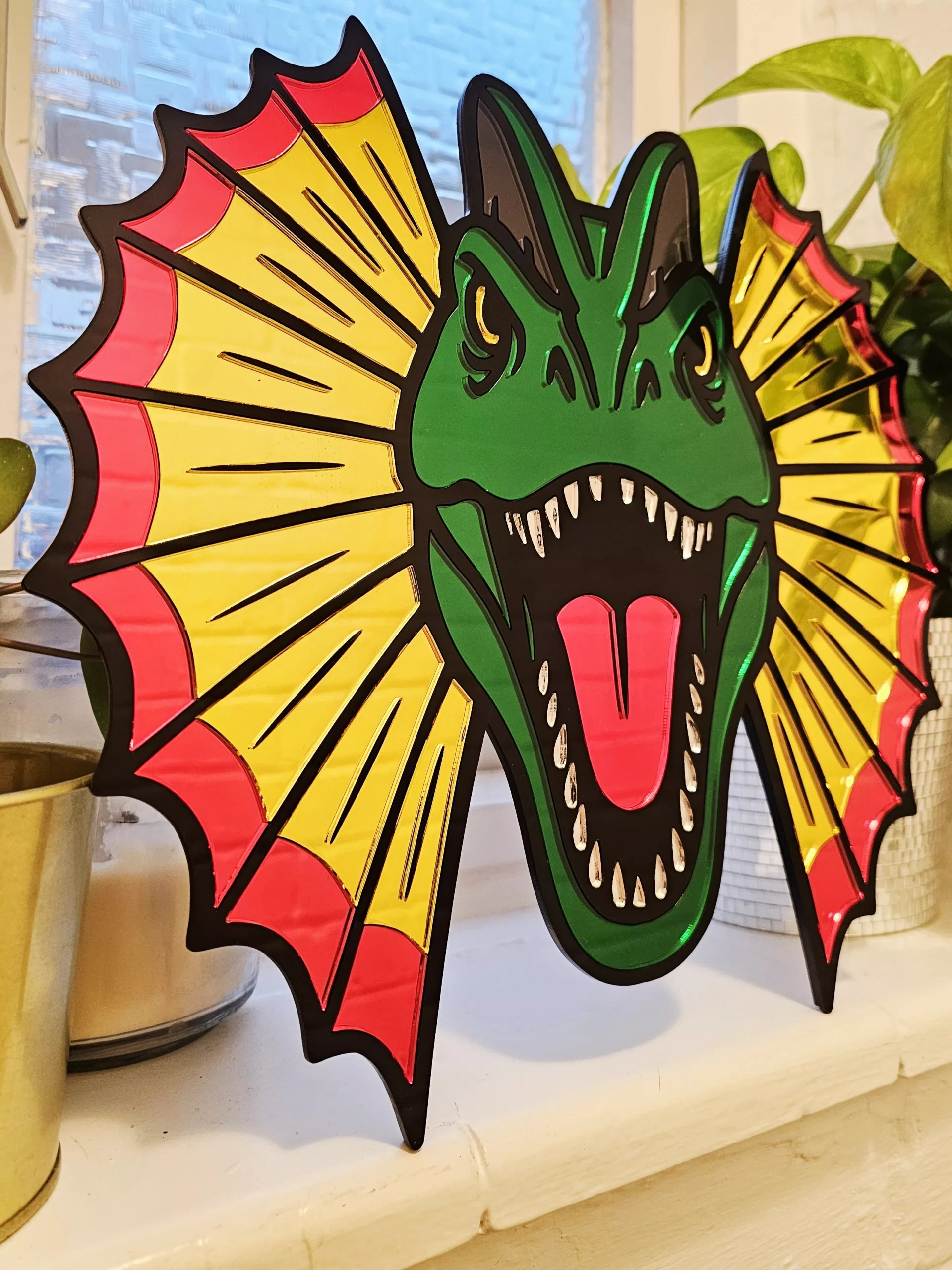 Colourful mirrored acrylic wall art in the shape of a Dilophosaurus dinosaur.