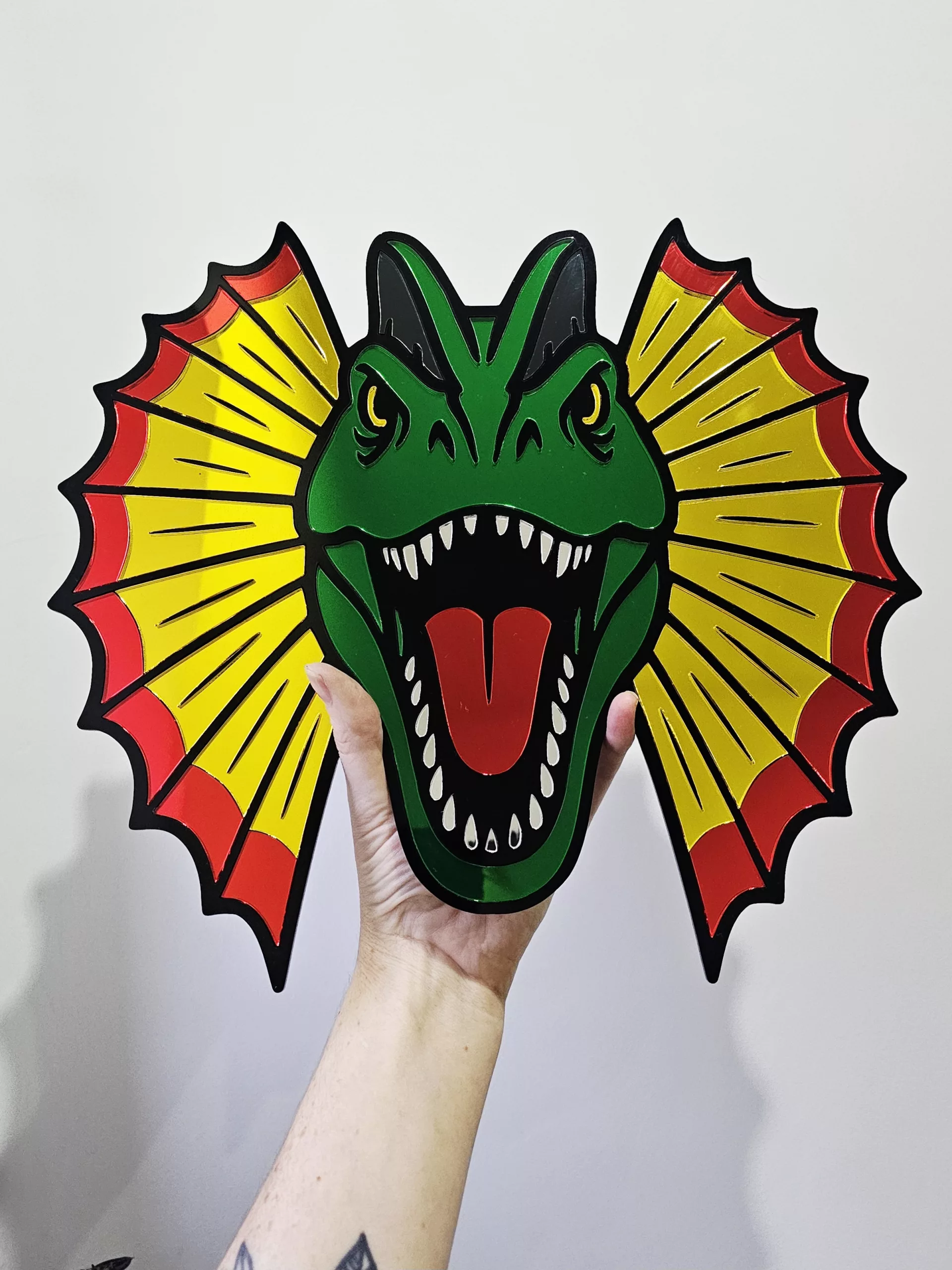 Colourful mirrored acrylic wall art in the shape of a Dilophosaurus dinosaur.
