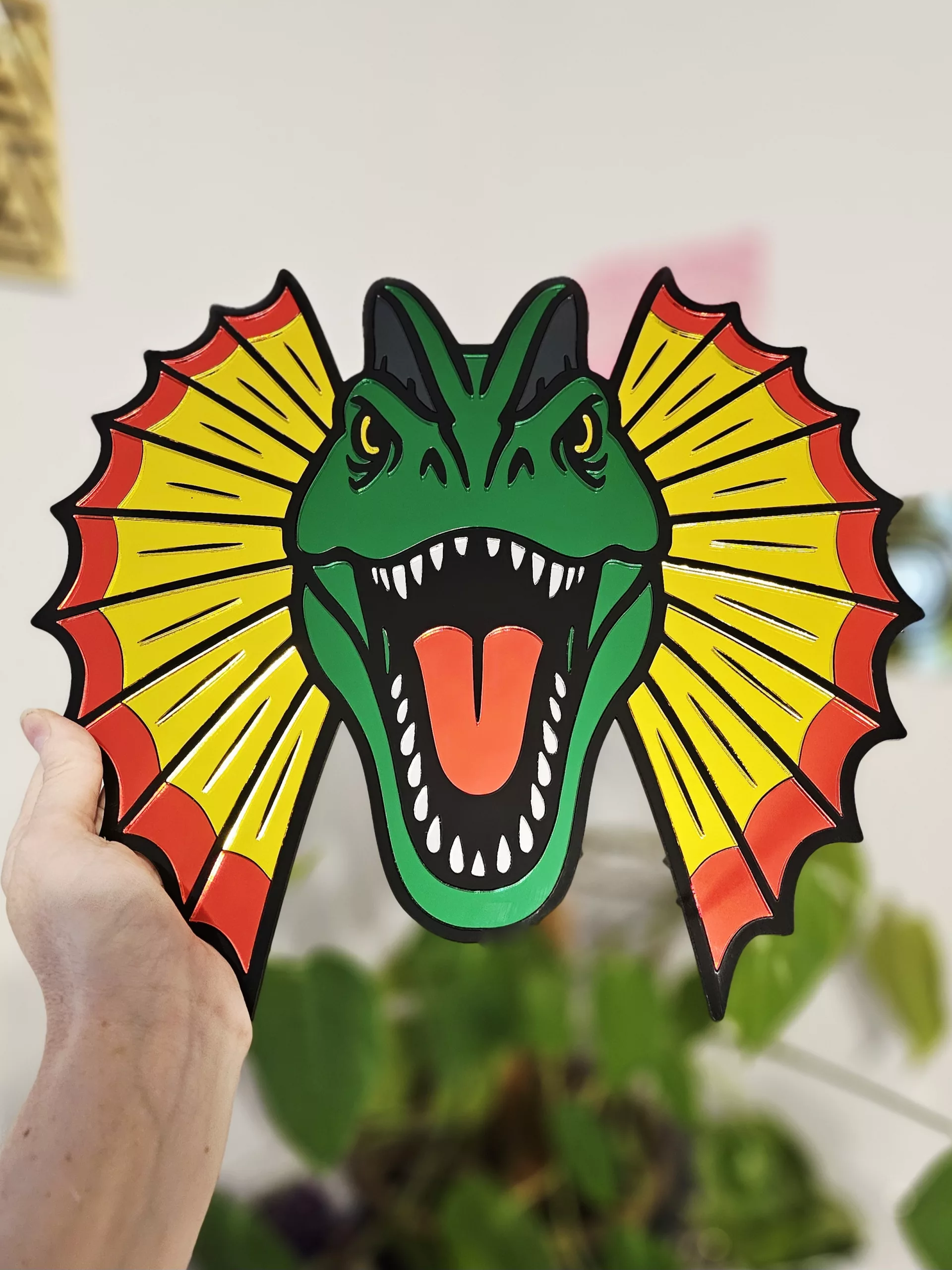 Colourful mirrored acrylic wall art in the shape of a Dilophosaurus dinosaur.