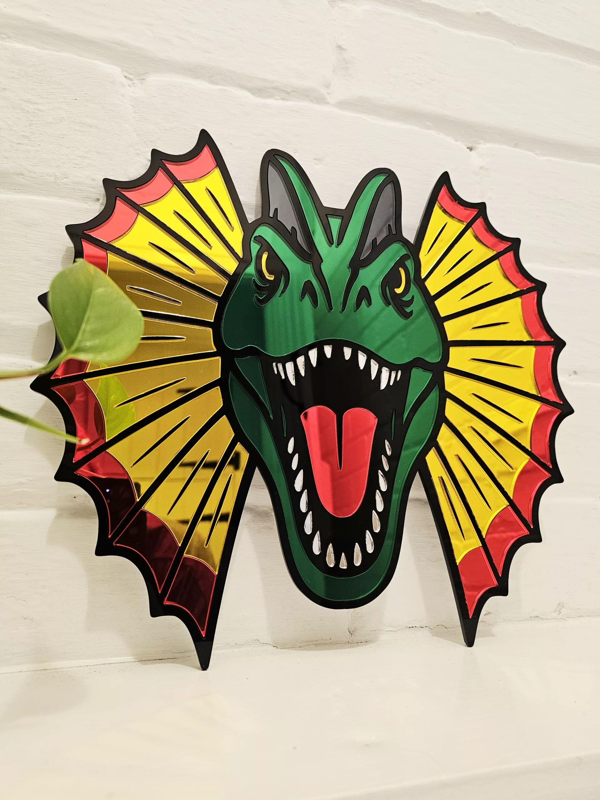 Colourful mirrored acrylic wall art in the shape of a Dilophosaurus dinosaur.