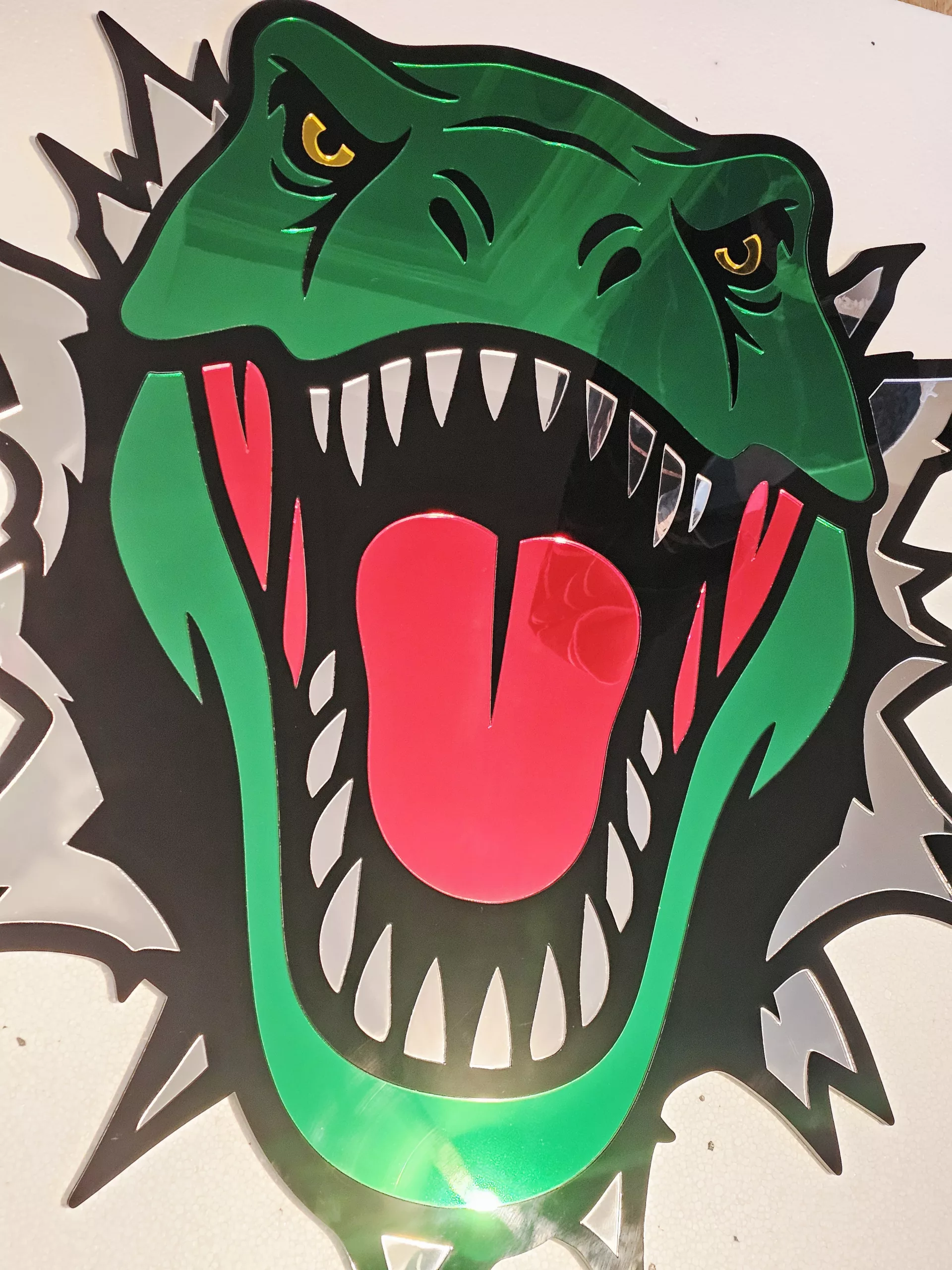 Coloured mirrored acrylic wall art in the shape of a T-Rex dinosaur
