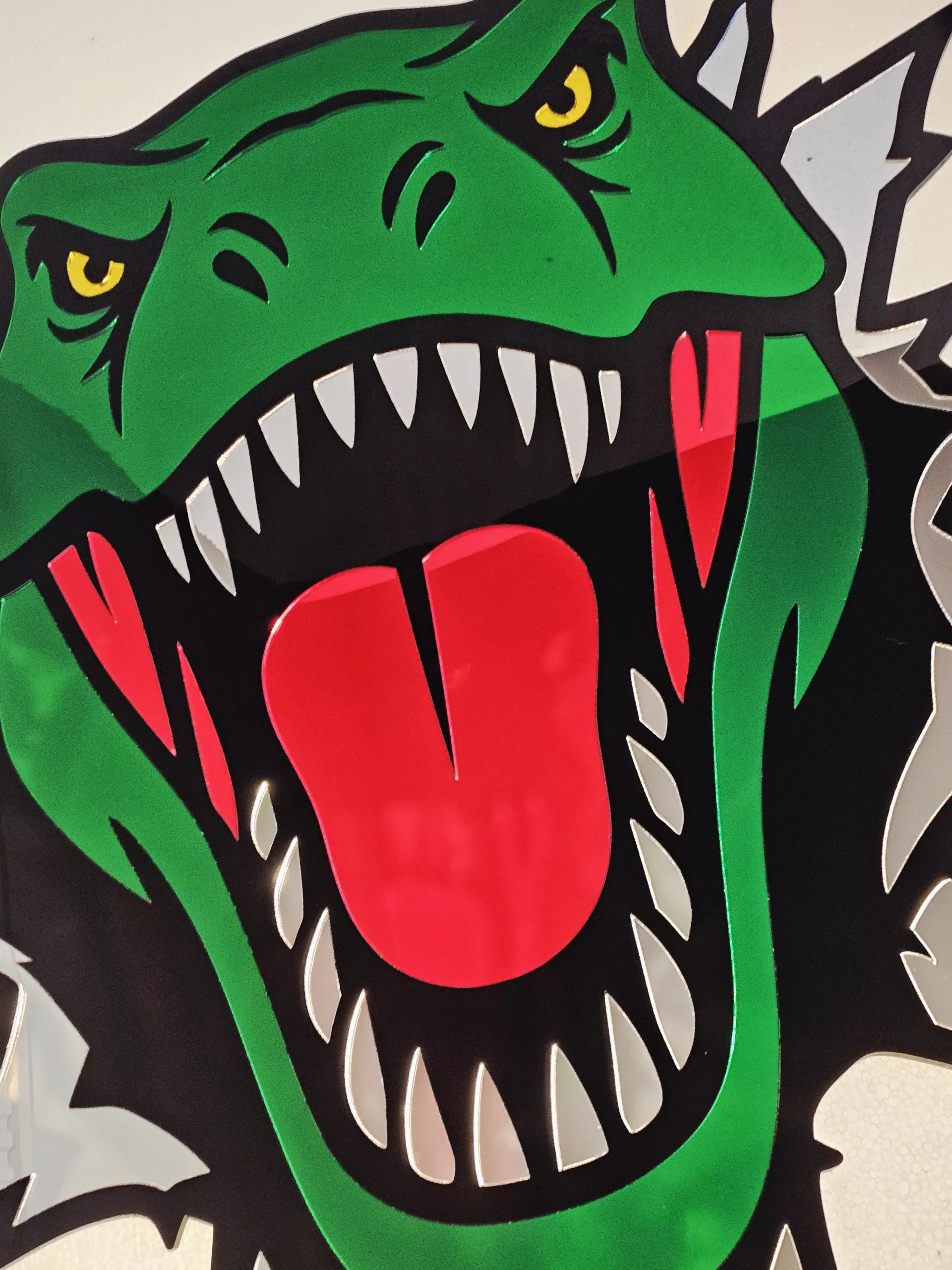 Coloured mirrored acrylic wall art in the shape of a T-Rex dinosaur