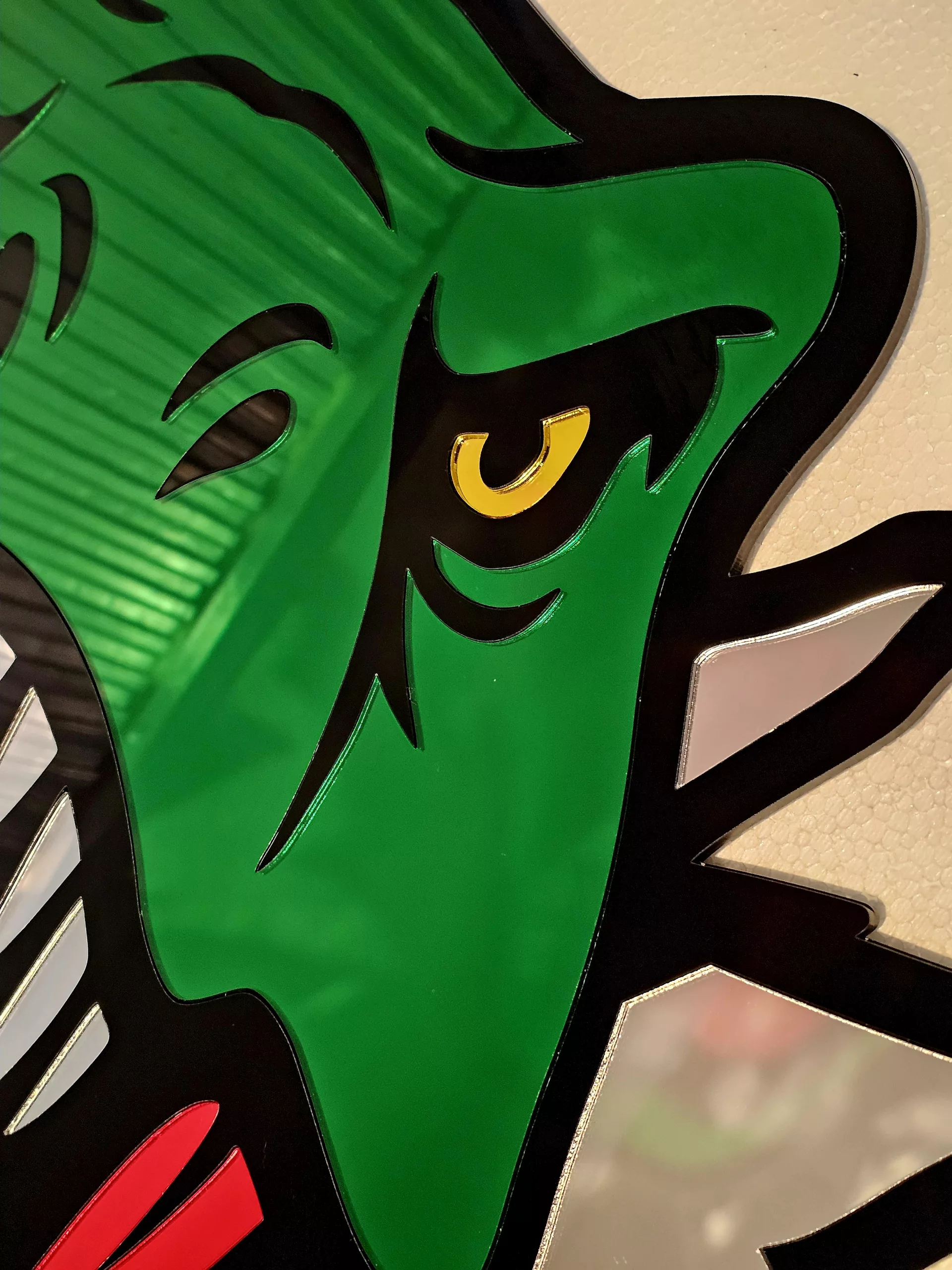 Coloured mirrored acrylic wall art in the shape of a T-Rex dinosaur