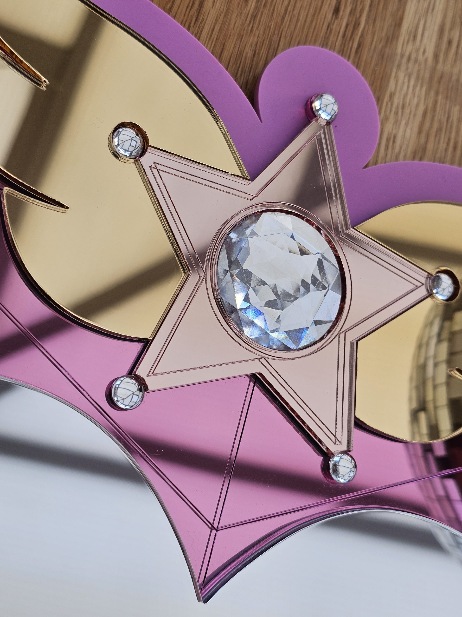 Details of a pink heart mirror, including a rose gold star inlaid with clear crystal.