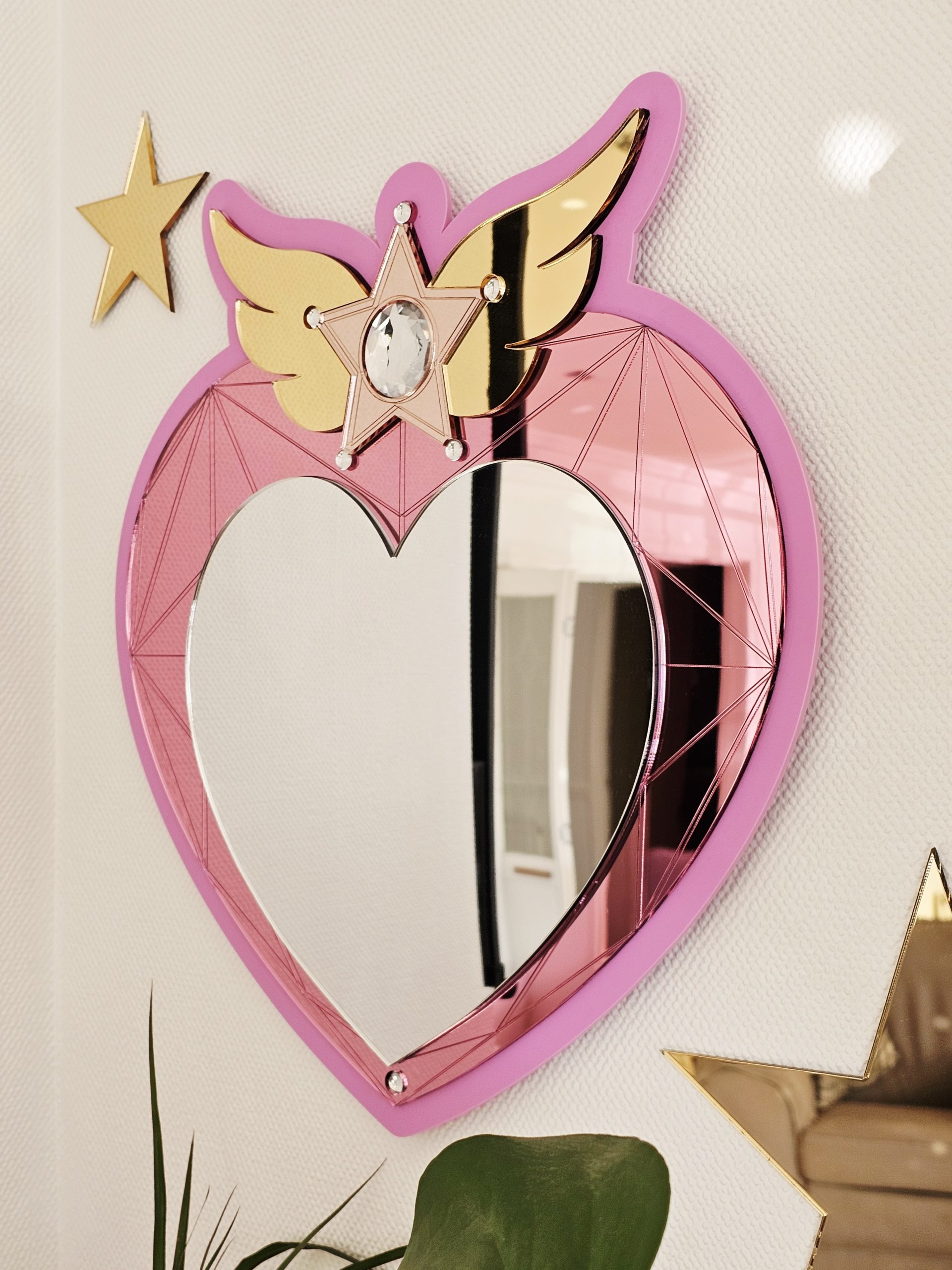 A heart mirror. Woth pink frame, layered with pink and silver heart, with details including gold wings inlaid with crystals.